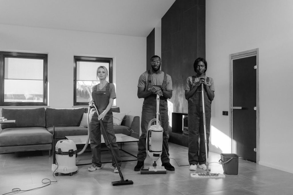 man-and-woman-standing-while-holding-vacuum-cleaner-6195120 A team of three professional cleaners in uniforms with equipment ready for housekeeping.